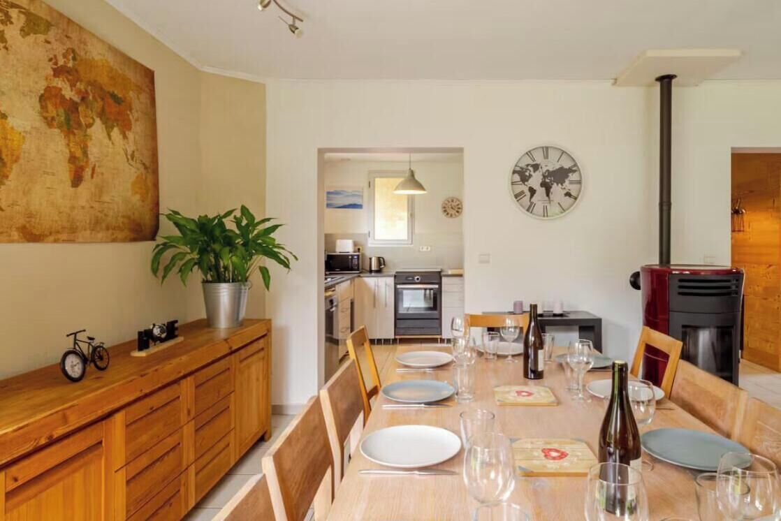 A dining area with a wooden table set for four, a potted plant, and a world map on the wall.