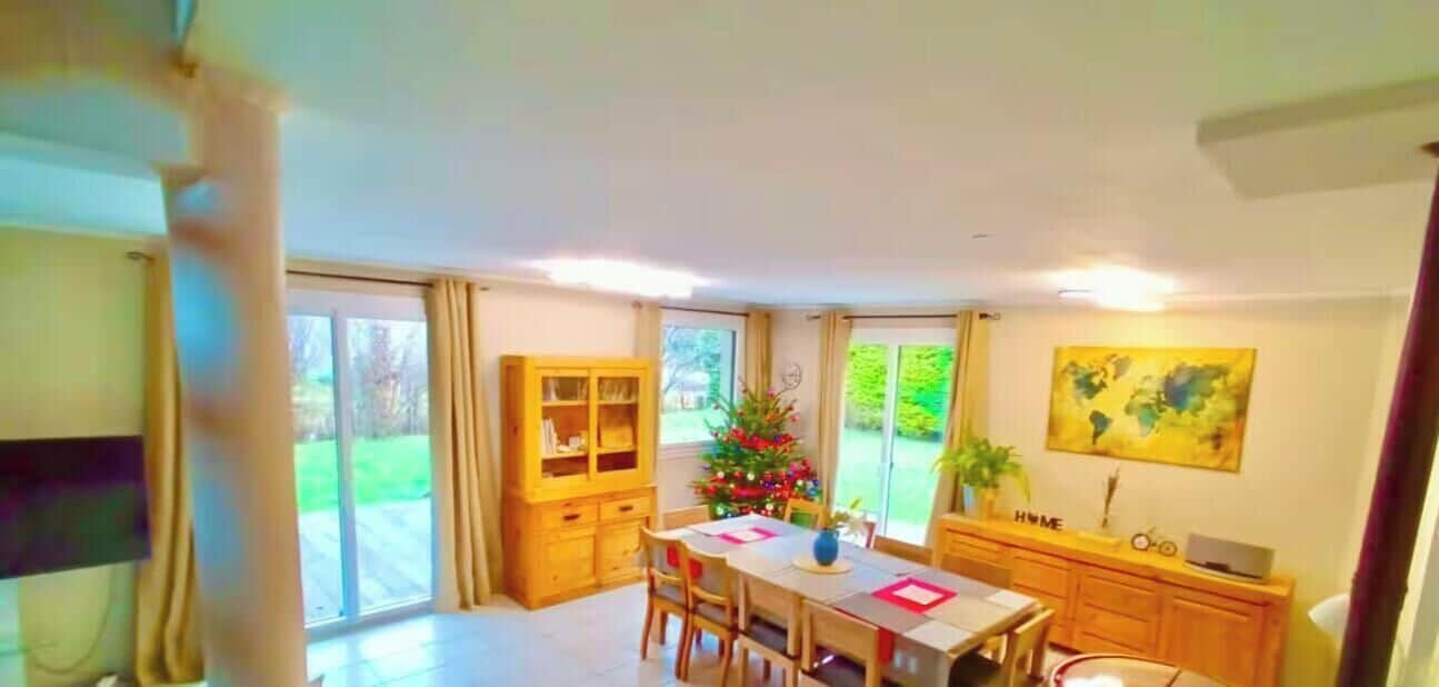 A dining area with a table, chairs, a Christmas tree, and a view of the outdoors.