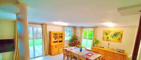 A dining area with a table, chairs, a Christmas tree, and a view of the outdoors.