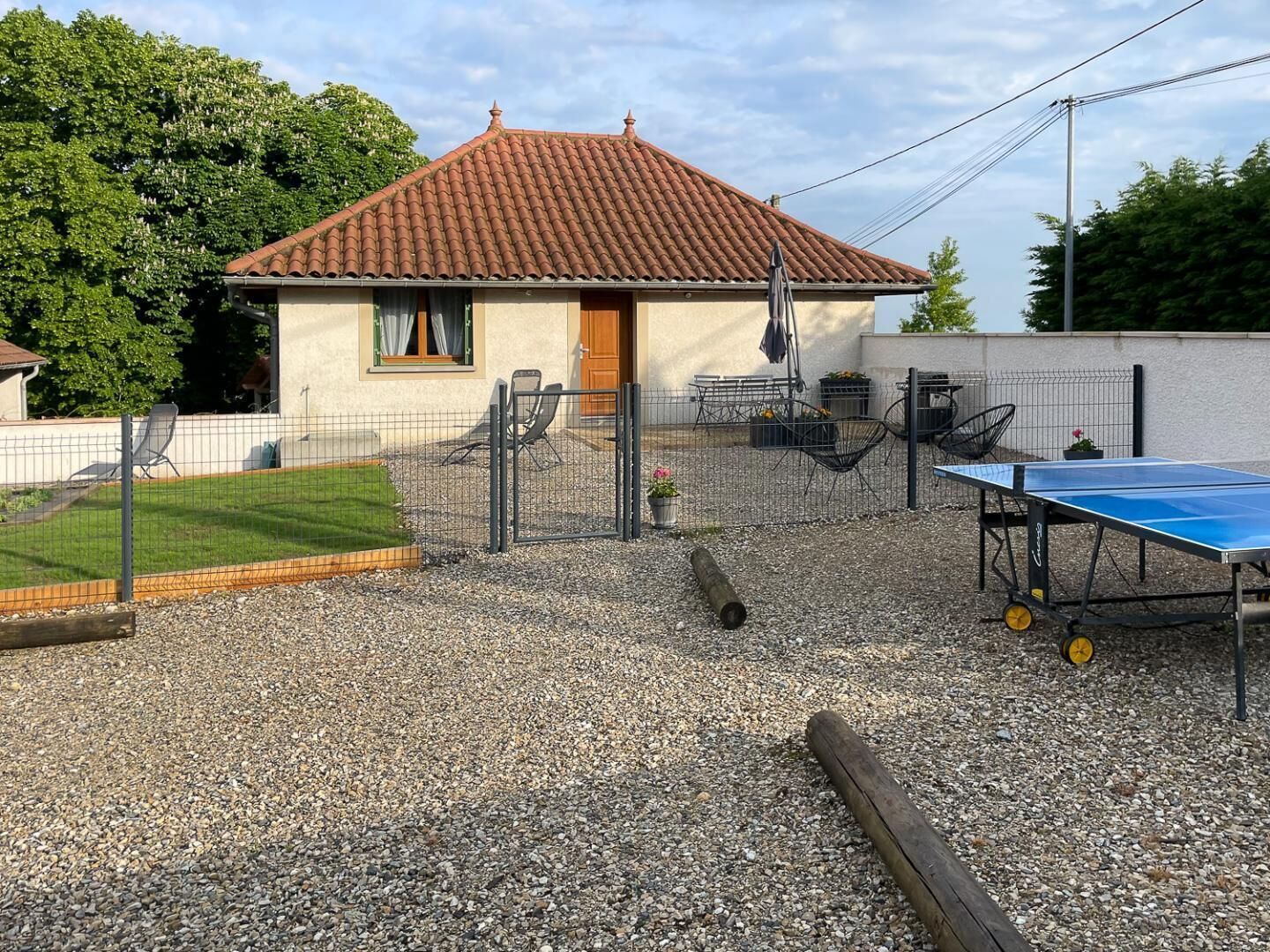 Une maison avec un toit en tuiles, un espace extérieur clôturé et une table de ping-pong.