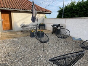 A patio area with outdoor seating, a barbecue grill, and a covered umbrella. - Gîte des Rabataux - DOISSIN (DOISSIN)