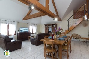 Un grand espace de vie comprenant une table à manger, des canapés et un téléviseur.