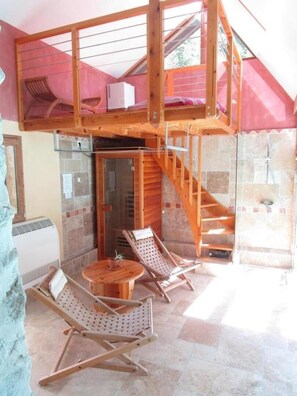 A room with a wooden staircase leading to a loft area, a glass shower enclosure, and a seating area with a round table and chairs. - The MieuZêtre Barn - SAINT QUENTIN SUR ISERE (SAINT QUENTIN SUR ISERE)
