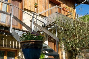 Ein Holzgebäude mit Metalltreppe und einem Blumentopf.