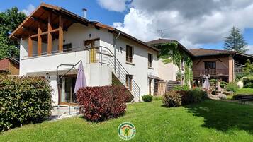 A two-story house with a wooden balcony, a staircase, and a well-maintained garden.
