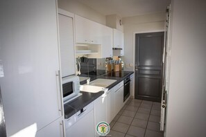 A compact kitchen with a microwave, sink, and stainless steel appliances. - Maison La Blanche - 4**** (AUTRANS-MEAUDRE EN VERCORS)