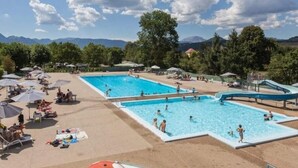 A swimming pool area with multiple pools, umbrellas, and lounge chairs.