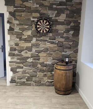 Una pared de piedra con un dardo y un barril de madera.