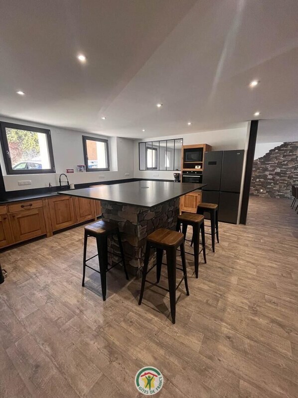 Una cocina moderna con una isla central, taburetes de bar, armarios de madera y una pared de acento de piedra.