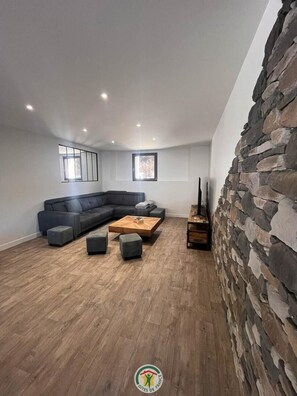 A modern living room with a sectional sofa, a wooden coffee table, and a stone accent wall. - Les Babelets - 4**** (VILLARD DE LANS)