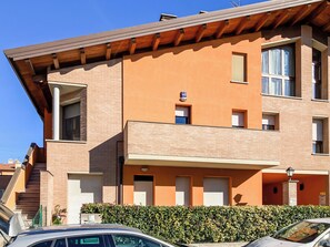 Un edificio de varios pisos con fachada de ladrillo, una entrada visible y un coche estacionado frente a él.