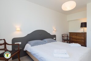 Ein Schlafzimmer mit einem Bett, zwei Wandlampen, einer Holzkommode und einem Sessel.