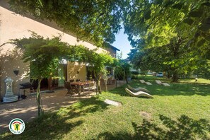 Un patio con zona de comedor, asientos al aire libre y una pérgola que proporciona sombra.