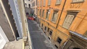 Une rue étroite, bordée de bâtiments des deux côtés, avec une borne d’incendie bien visible et un camion rouge garé sur le bord.