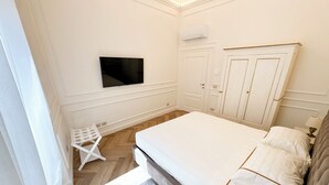 Une chambre à coucher avec un lit, une armoire et un téléviseur fixé au mur.