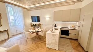 Une cuisine moderne dotée d’un four encastré, d’un coin repas avec une table en verre et d’une cheminée.