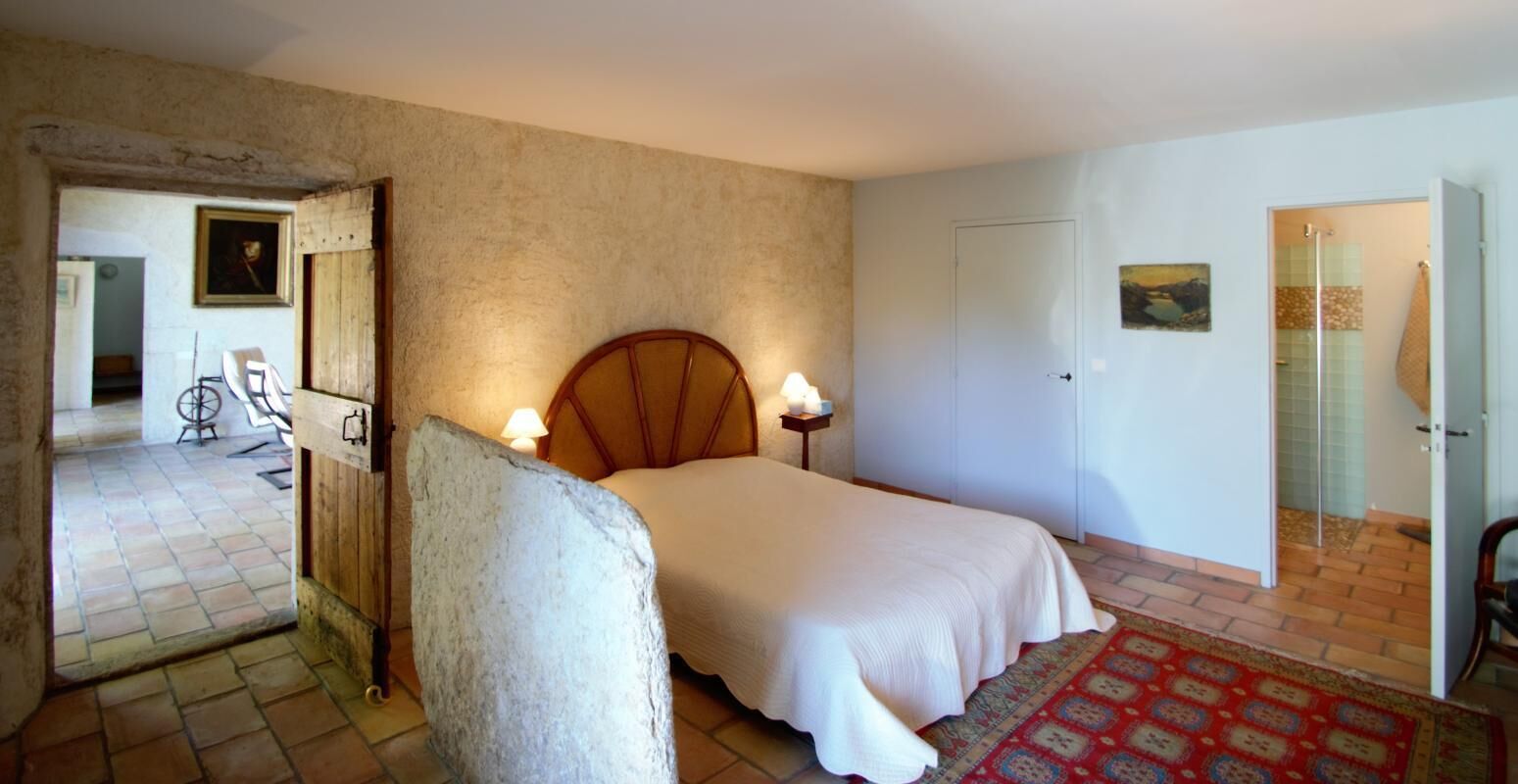 Ein Schlafzimmer mit einem Bett, Nachttischlampen, einem Holzkopfteil, einer Tür und einem gemusterten Teppich.