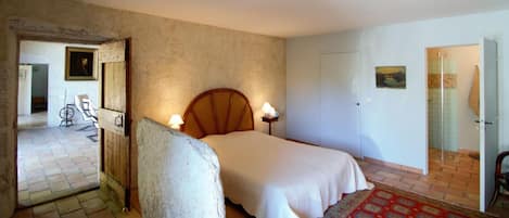 Une chambre à coucher avec un lit, des lampes de chevet, une tête de lit en bois, une porte et un tapis à motifs.
