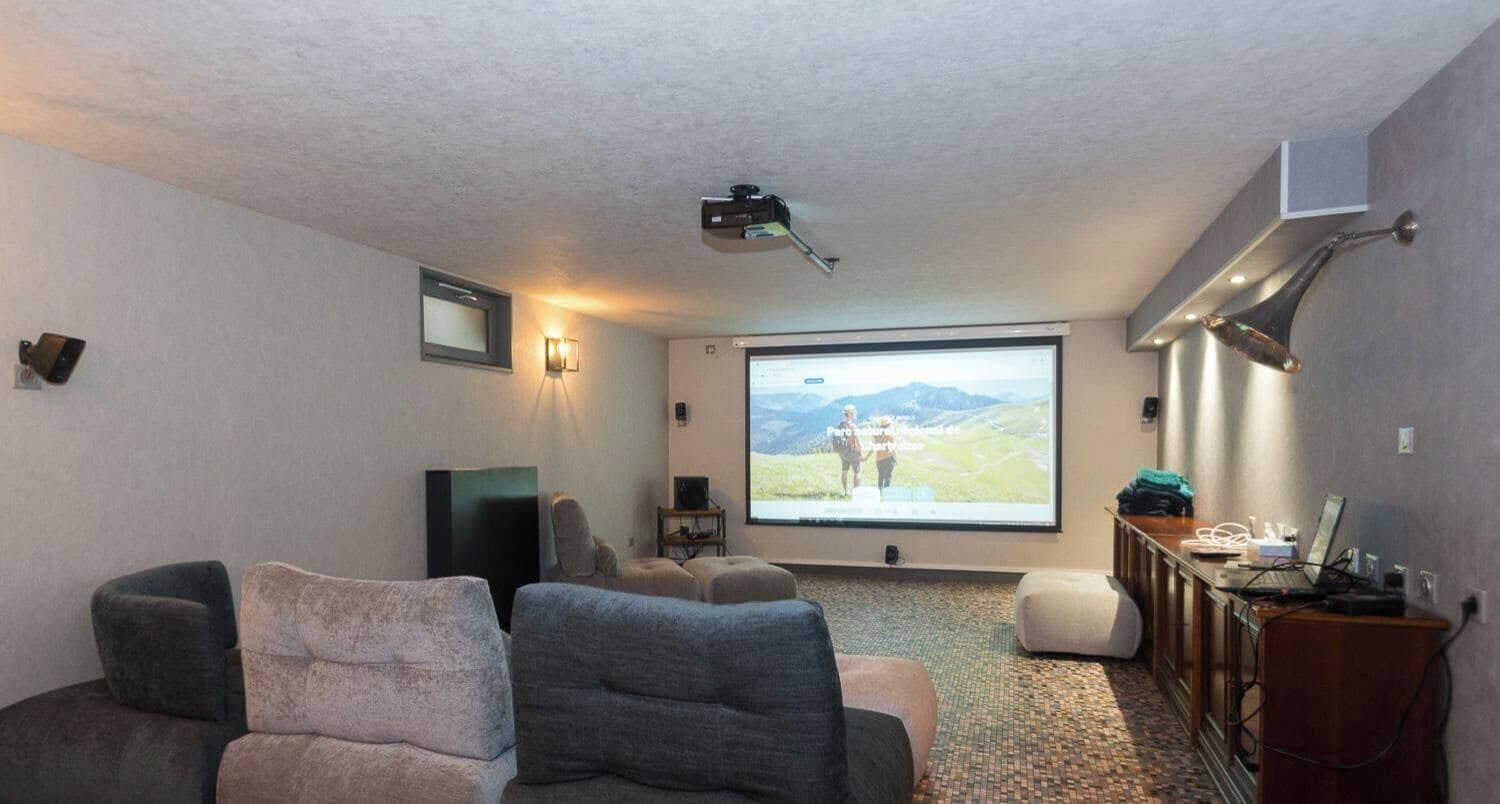 A home theater room with a large screen, comfortable seating, and a projector.