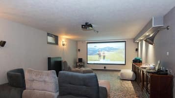 A home theater room with a large screen, comfortable seating, and a projector.