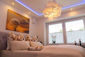 A bedroom with a large bed, a painting, and a window with a view.