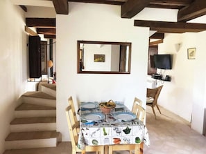 A dining area with a table set for four, a television mounted on the wall, and a staircase leading to another room. - Villa la Dolcevita by Interhome (Magliano di Tenna)