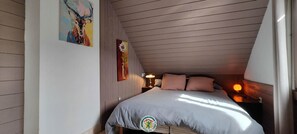 A bedroom with a bed, a nightstand, a lamp, and two wall-mounted paintings. - Clémence's Farm 5***** (VILLARD DE LANS)