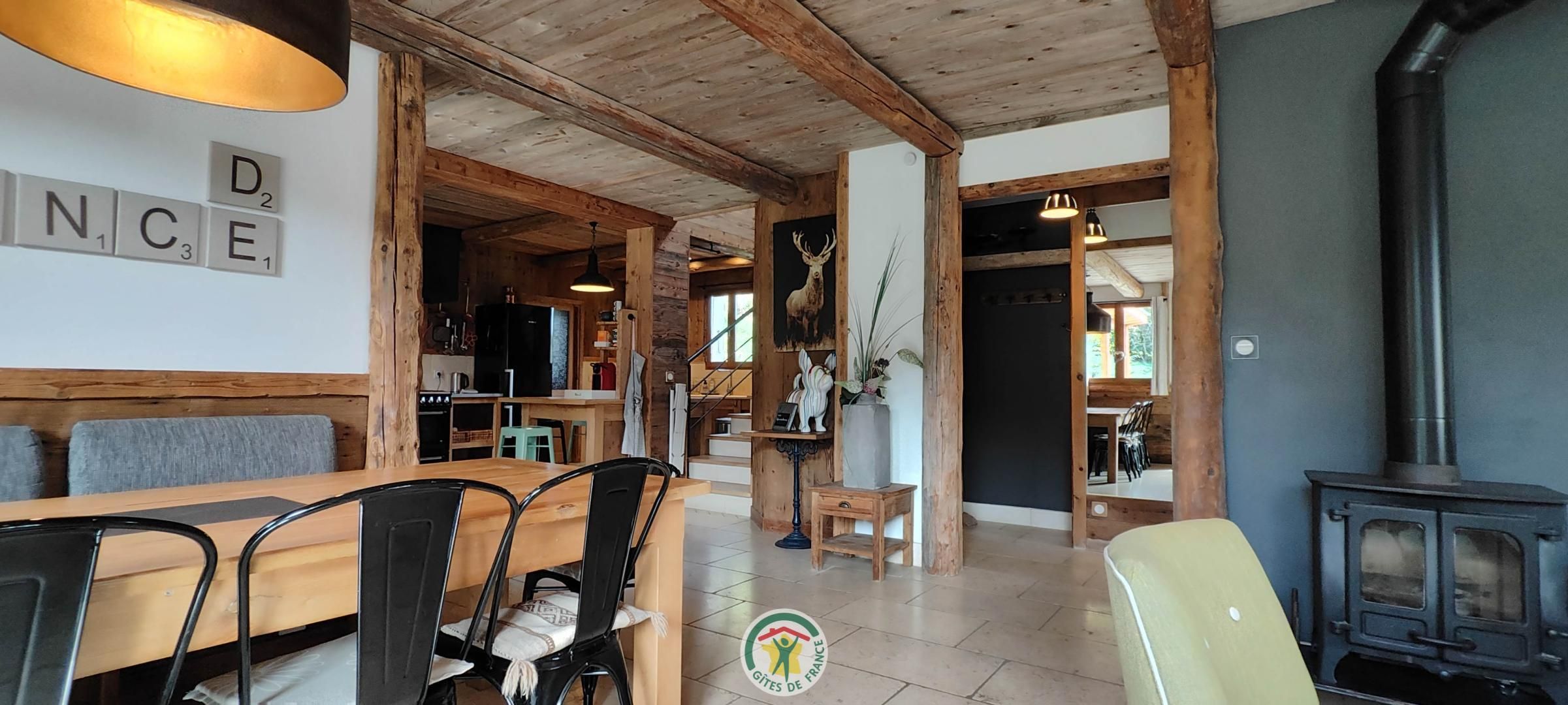 Een rustiek interieur met een houten eettafel, stoelen, een bank, een open haard en een keuken.