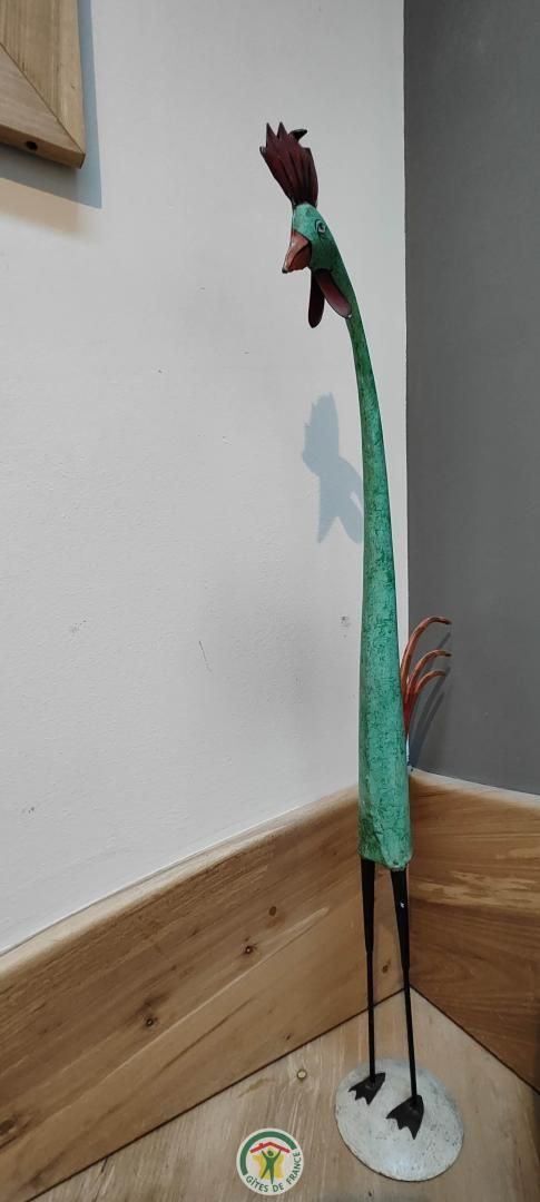 Een beeldje van een haan op een houten vloer.