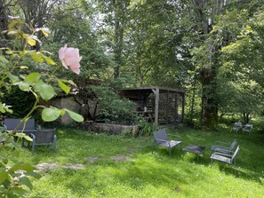 A rustic outdoor seating area with metal chairs and tables, surrounded by lush greenery and trees. - The Two Brothers' Farm (AUTRANS MEAUDRE EN VERCORS)