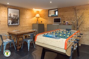 A room with a foosball table, a wooden desk with chairs, a lamp, a television, and a framed picture on the wall. - The Two Brothers' Farm (AUTRANS MEAUDRE EN VERCORS)