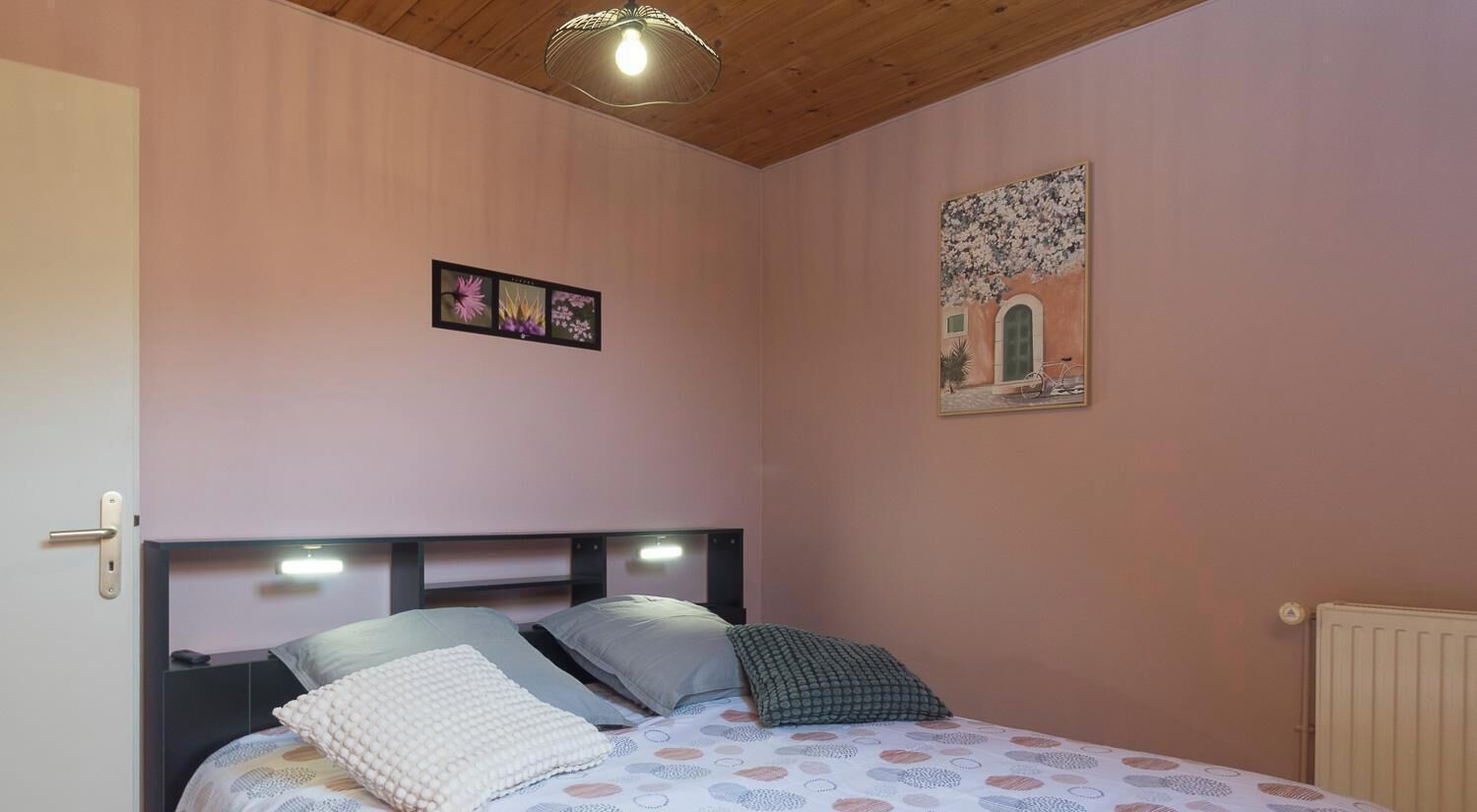 Een slaapkamer met een bed, een wandlamp en een ingelijste foto.