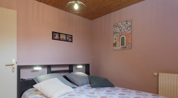 A bedroom with a bed, a wall-mounted light fixture, and a framed picture. - L'Etoile du Colombier (VALBONNAIS)