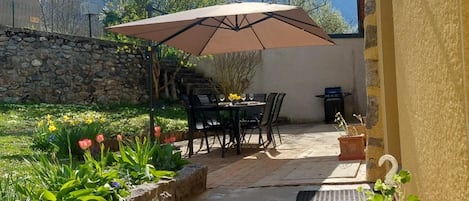 An outdoor patio with a table and chairs, a stone wall, and a mountain view.