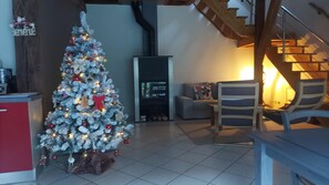 Un salon avec un sapin de Noël décoré, une cheminée et un escalier.