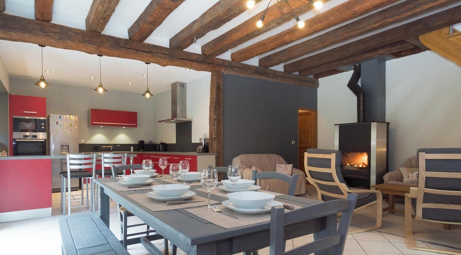 A modern kitchen with red cabinets, a dining area with a table set for four, and a fireplace.