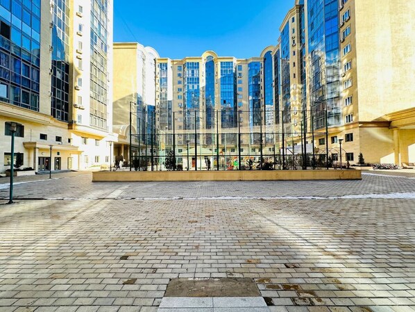 A spacious plaza with a modern building featuring large windows and a yellow facade.