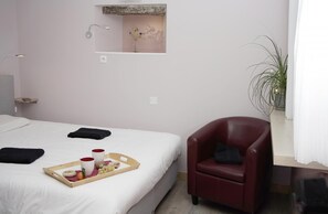 A hotel room with a bed, a red armchair, a tray with food, and a small mirror on the wall. - The Plantier Estate Guesthouse (SAINT HILAIRE DE LA COTE)