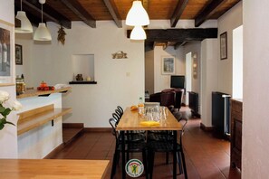 Un espace repas avec une table en bois, des chaises et des lampes suspendues.