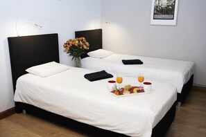 A hotel room with two beds, a tray with fruit and juice, and a framed picture on the wall. - The Plantier Estate Guesthouse (SAINT HILAIRE DE LA COTE)