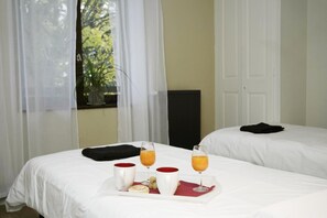 A hotel room with two beds, a tray with breakfast items, and a window with curtains. - The Plantier Estate Guesthouse (SAINT HILAIRE DE LA COTE)