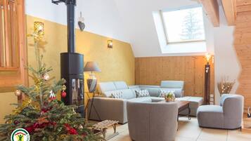 Un salon chaleureux avec une cheminée, un ensemble de canapés, un sapin de Noël et une lucarne.