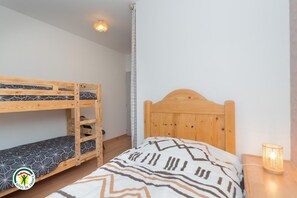 A bedroom with a bunk bed, a single bed, a bedside lamp, and a ceiling light fixture. - The Violets of Grand Veymont (GRESSE EN VERCORS)