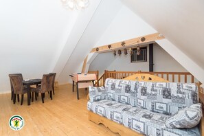 A loft bedroom with a wooden floor, a sofa, a desk, and a chair. - The Violets of Grand Veymont (GRESSE EN VERCORS)