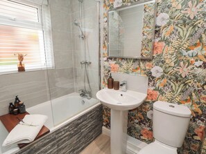 A bathroom with a glass-enclosed shower, a white pedestal sink, and a toilet. - Acorn Cottage (Yarm)