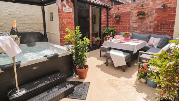 A patio area with a hot tub, seating, and potted plants. - Acorn Cottage (Yarm)