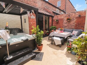 A patio area with a hot tub, seating, and potted plants. - Acorn Cottage (Yarm)