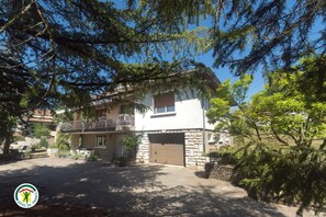 Une maison à deux étages avec un balcon, un garage et une façade en pierre.