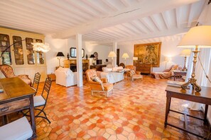 A spacious living room with a tiled floor, a fireplace, and a large painting on the wall. - Les Jacines - SUCCIEU (SUCCIEU)