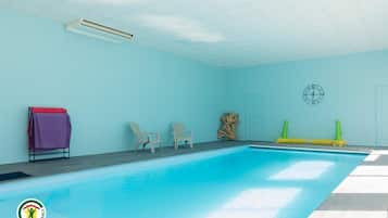 An indoor swimming pool with a tiled floor, two chairs, a door, and a clock on the wall.